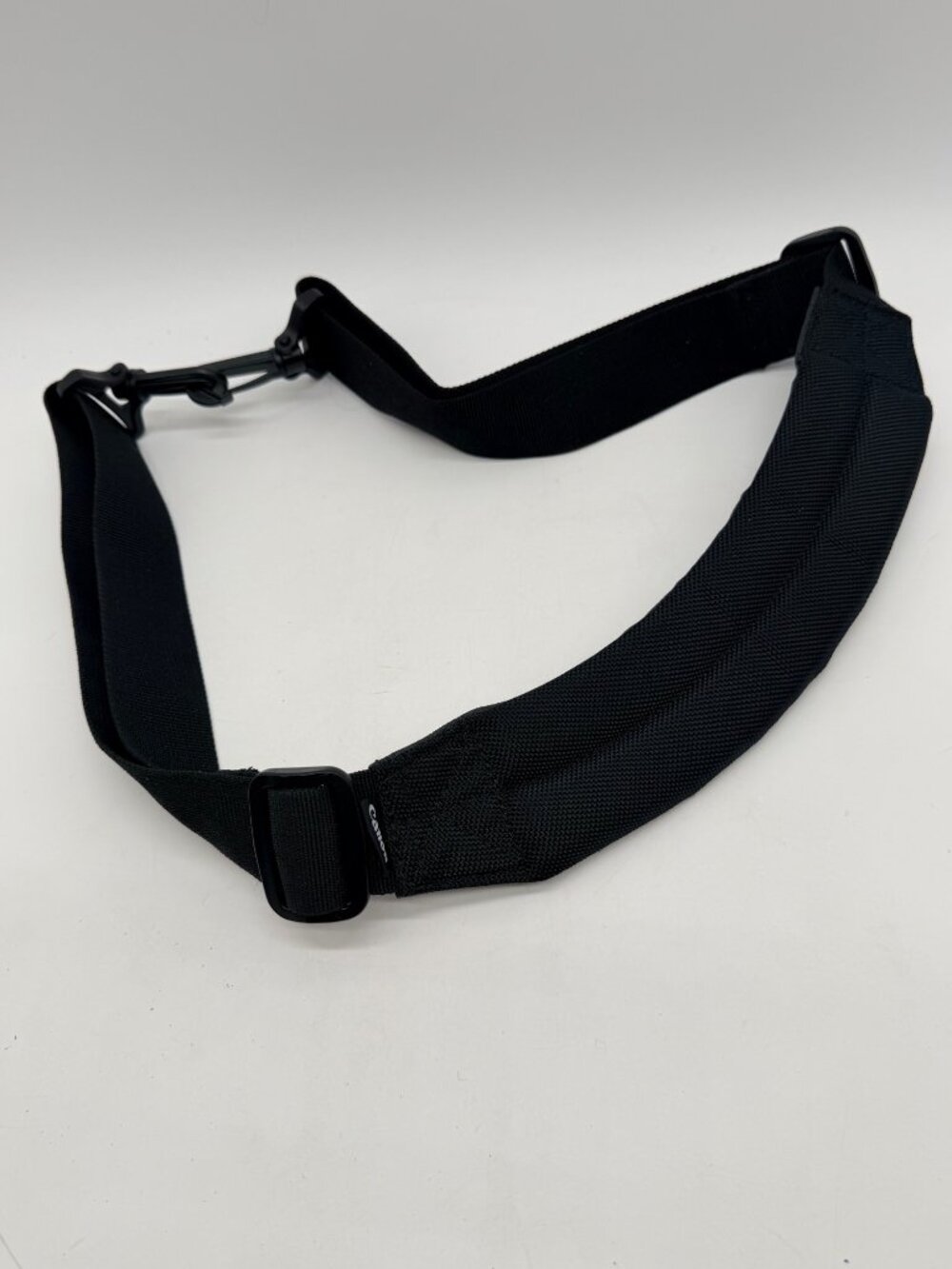 black Canon padded camera shoulder strap featuring an adjustable nylon web belt